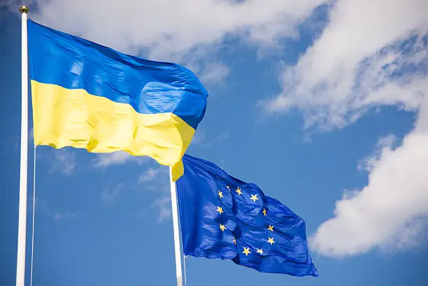 Flags of Ukraine and European Union (EU) with blue sky background