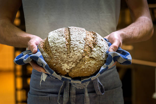 baker mit frischen, warme brot. - weizenvollkorn stock-fotos und bilder