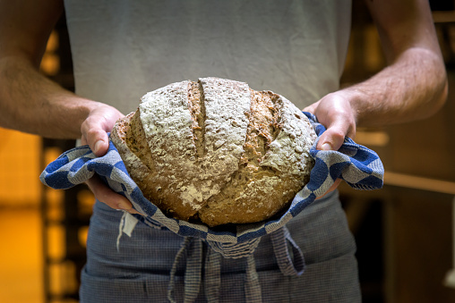 Baker shot in bakery, with warm bread just out of the oven