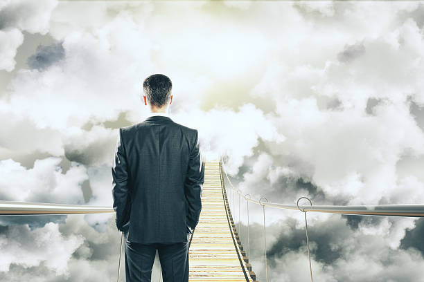 istock Businessman is walking on air bridge among the clouds concept 497632594