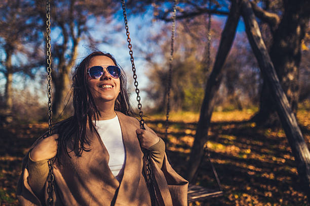 istock Happy young woman smiling on swing 497635474