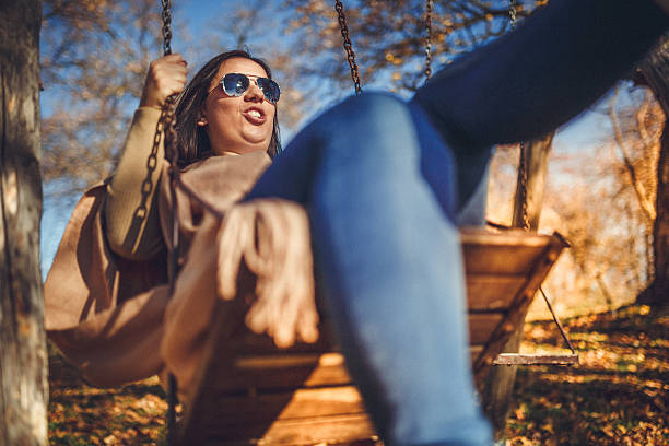 istock Happy young woman smiling on swing 497635884