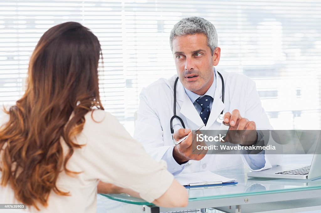 Doctor talking with his patient seriously Doctor talking with his patient seriously in medical office 30-39 Years Stock Photo