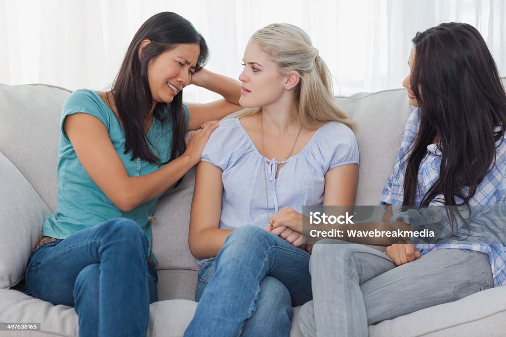 Friends listening to crying woman Friends listening to crying woman at home on the couch 20-29 Years Stock Photo