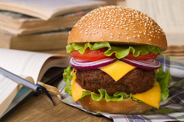 Lunch during study: Fresh big hamburger Lunch during study: Fresh big hamburger on a background of notebooks and textbooks. Closeup horizontal beef pad stock pictures, royalty-free photos & images