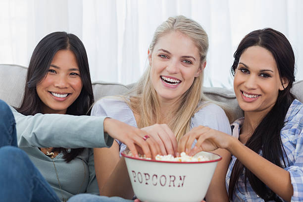 istock Friends sharing bowl of popcorn and watching tv 497639979