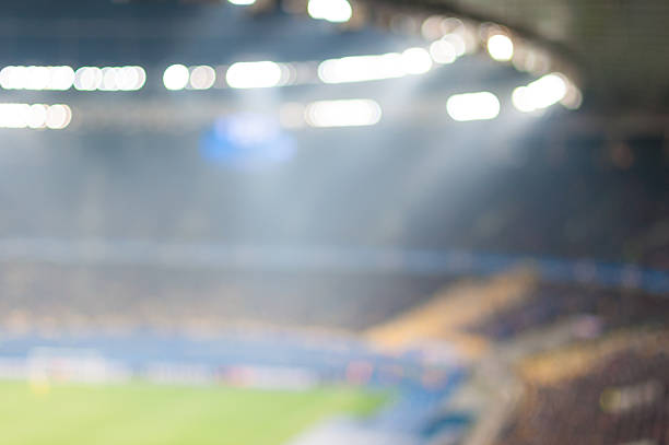 Blurred crowded football stadium with field, stands and spectators. 2016