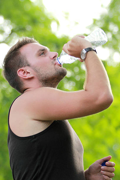 istock male runner drinking mineral water at the break after running 497655106