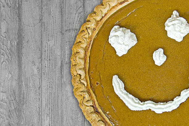 pumpkin pie with happy face Whipped cream happy face on fresh baked Thanksgiving pumpkin pie on rustic wood. funny thanksgiving stock pictures, royalty-free photos & images