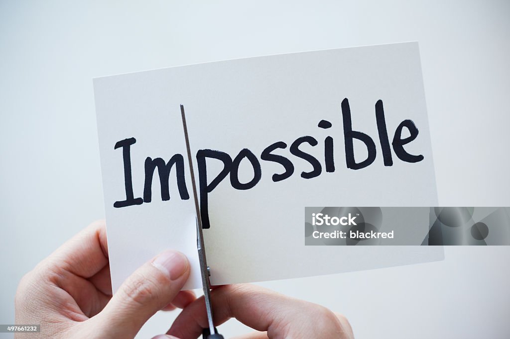 Using Scissors Cut the Word on Paper Impossible Become Possible Close-up of hand using scissors cutting the word on paper, Impossible become Possible. Scissors Stock Photo
