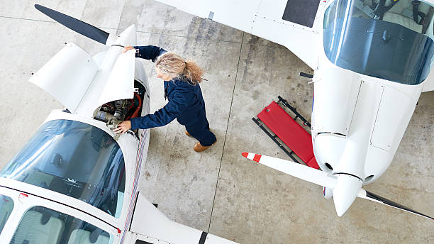 She is ready for difficulty Woman in coveralls opening side panel of aircraft to examine engine ultralight photos stock pictures, royalty-free photos & images