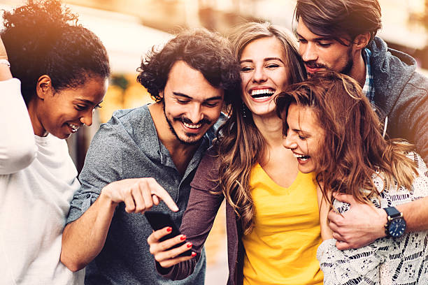 Friends with phone outdoors Ggroup of young friends at urban scene having fun five people photos stock pictures, royalty-free photos & images