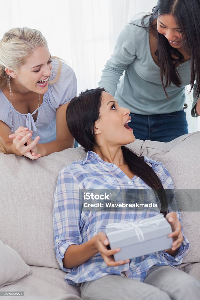 Friends surprising brunette with a present Friends surprising brunette with a present at home on couch 20-29 Years Stock Photo