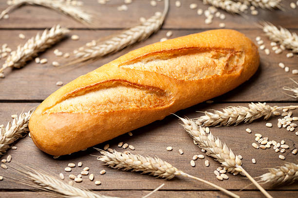 istock Baguette and wheat ears on wooden table 497684010