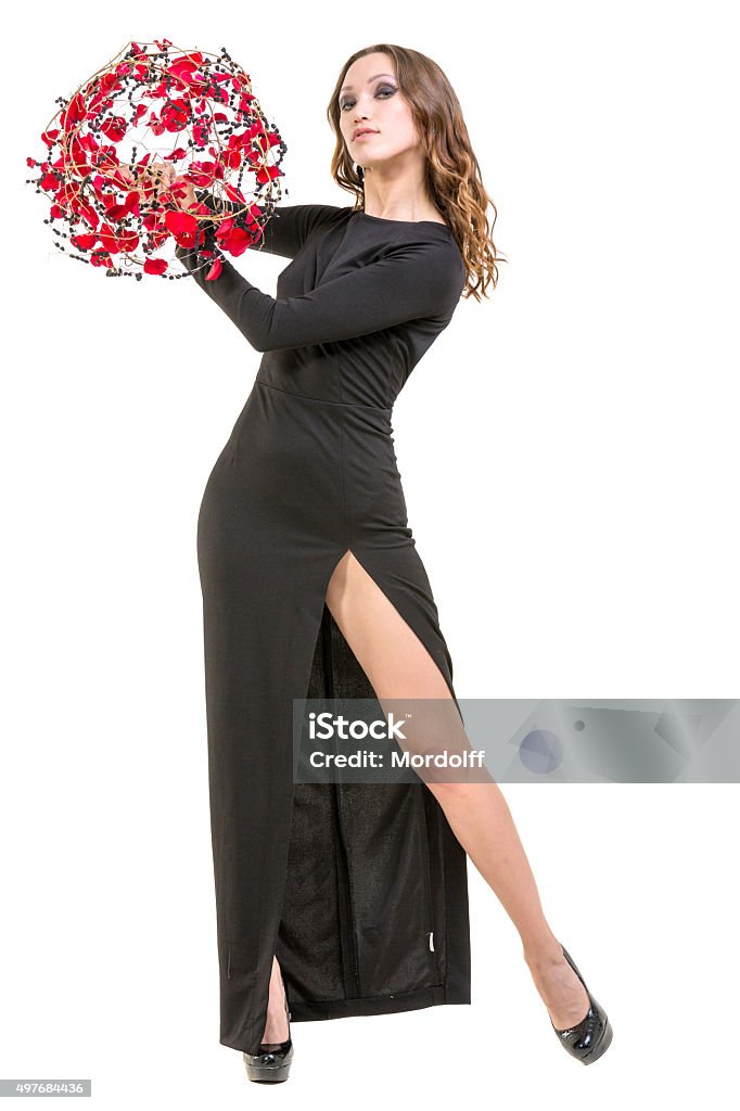 Charming Young Woman With Floral Arrangement in hands Beautiful young woman in a black evening dress posing with a flower arrangement in her hands. Studio shot, isolated on white 2015 Stock Photo