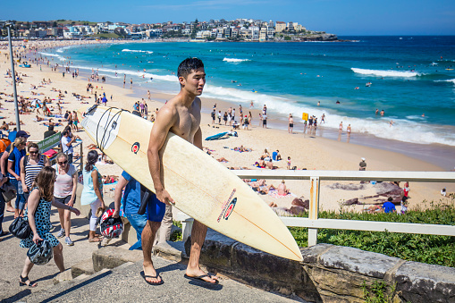 Sydney, Australia - November 19, 2015: Surfer coming out of Bondi beach with his surf board on a sunny day.