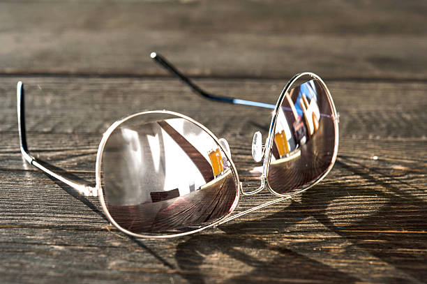 Metal thin trendy sunglasses on wooden table. Outdoors closeup. Metal thin trendy sunglasses on wooden table. Evening light.  Outdoors closeup. cool glasses hand colored sun stock pictures, royalty-free photos & images