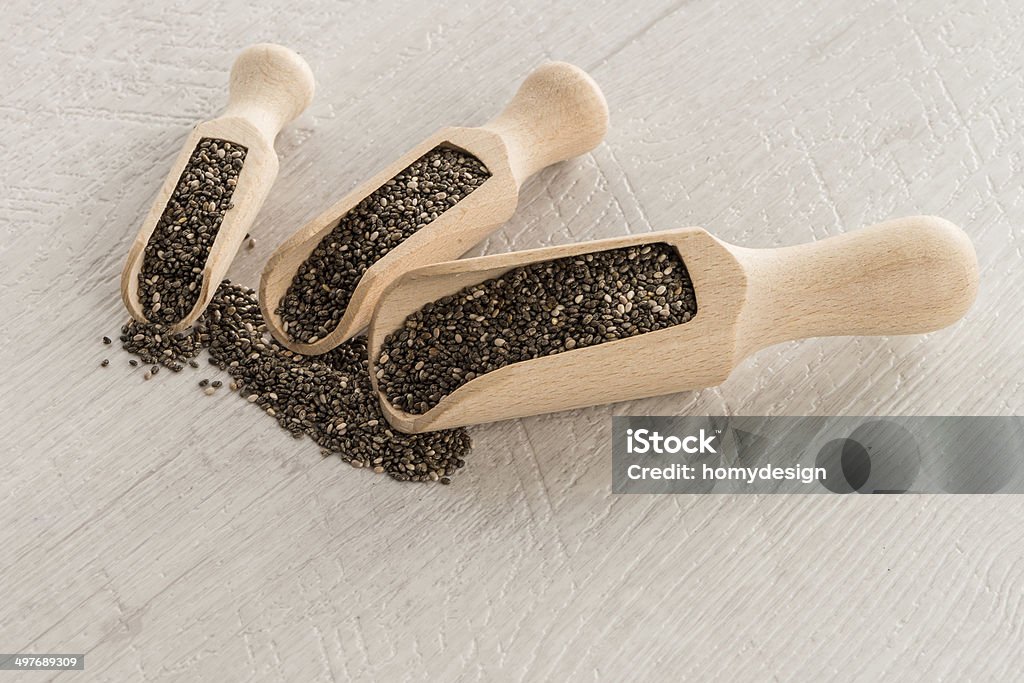 Chia seeds in wooden scoops Chia seeds in wooden scoops on wooden table. Antioxidant Stock Photo