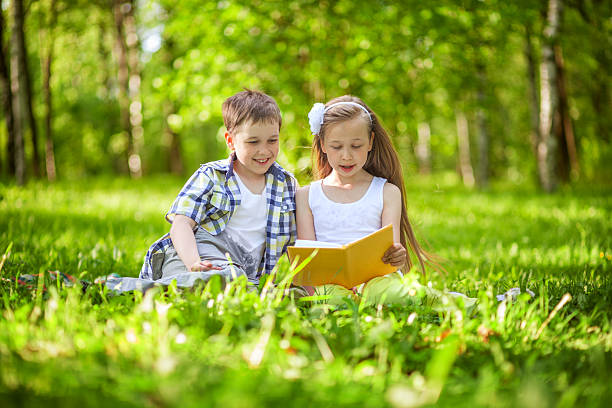 istock Children reading book in the summer park 497690189