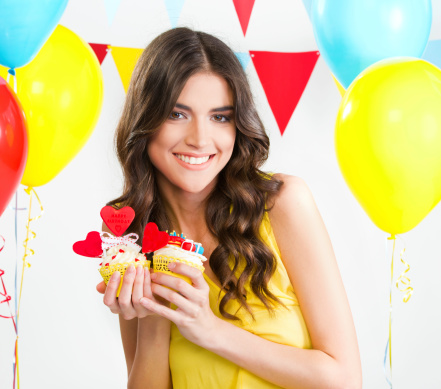 Beautiful woman holding two cupcakes