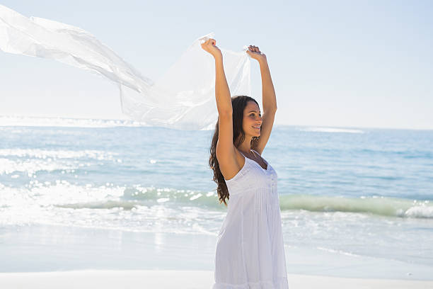 счастливый брюнетка в белом платье-солнце держит парео - women sarong beach white стоковые фото и изображения