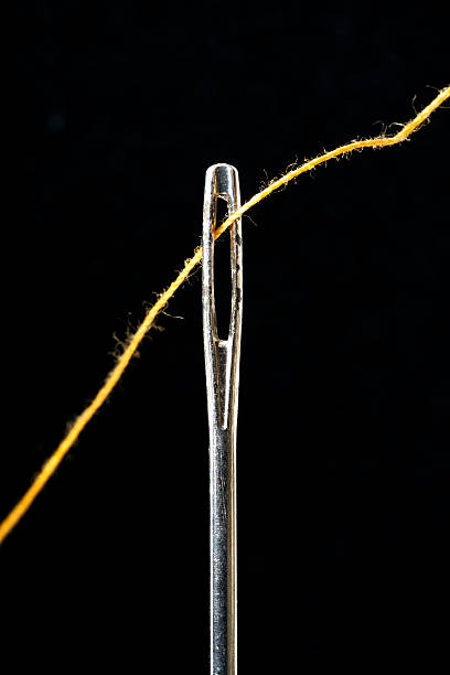 needle and thread on  black background stock photo