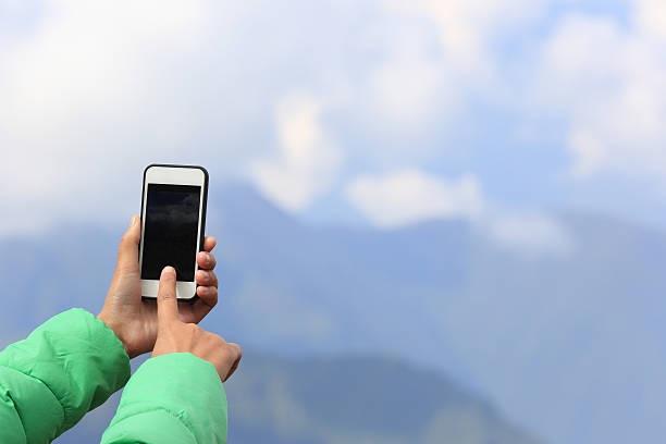 istock woman hands taking photo with smart phone on mountain peak 497703550