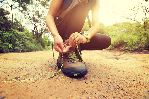 woman hiking tying shoelace on forest trail