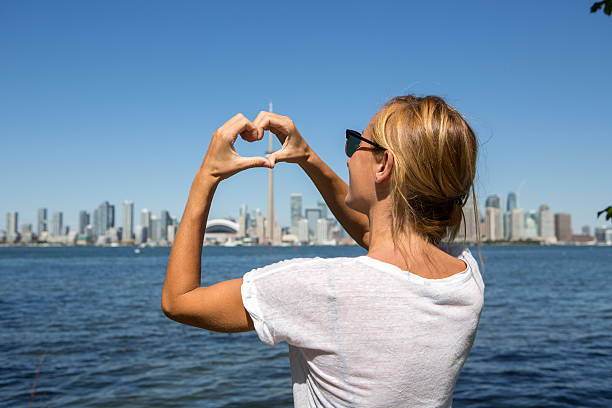 istock Young woman making heart shape frame to Toronto city 497704808
