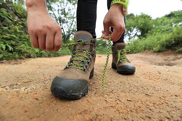 istock woman hiking tying shoelace on forest trail 497706234