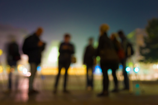 Backlight and silhouette of people at night in an urban environment with colored lights.
