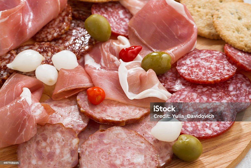 Assorted deli meat snacks, sausages and pickles on board Assorted deli meat snacks, sausages and pickles on board, close-up, horizontal 2015 Stock Photo