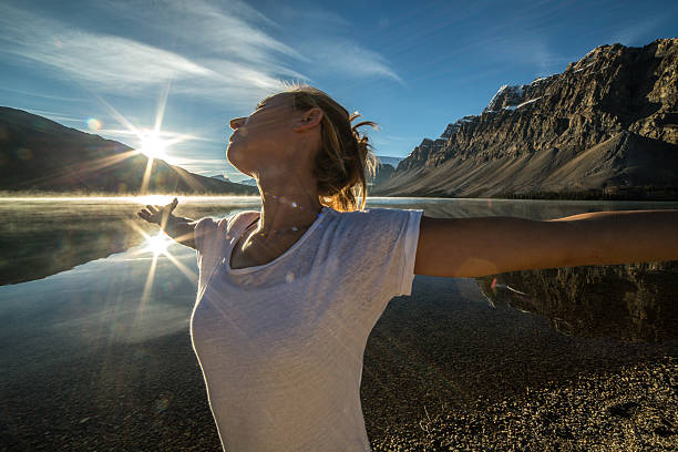 istock One woman by the lake arms outstretched embracing nature 497708708