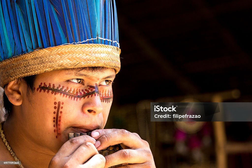 Native Brazilian playing wooden flute Native Brazilian man playing wooden flute at an indigenous tribe in the Amazon Indigenous Peoples of the Americas Stock Photo