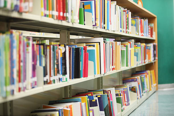 Asian little girl hand is finding and selecting a book on bookshelf in the library in vintage color tone