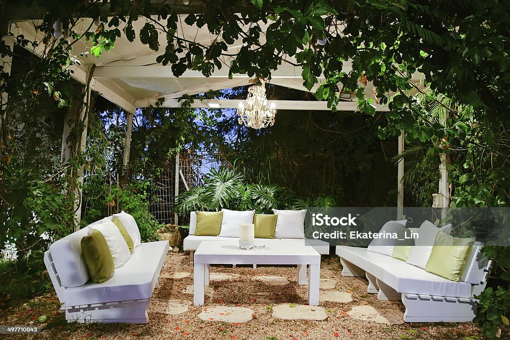 Romantic atmosphere, evening on the porch Patio romantic in the evening with benches and pillows chandelier and table Patio Stock Photo