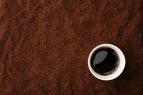 Overhead shot of black coffee in disposable cup Overhead shot of black coffee in disposable cup on ground coffee beans. black coffee from above stock pictures, royalty-free photos & images