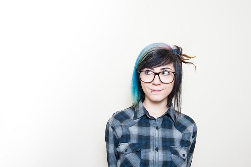 Smiling alternative teen woman in blue shirt looking out on white background