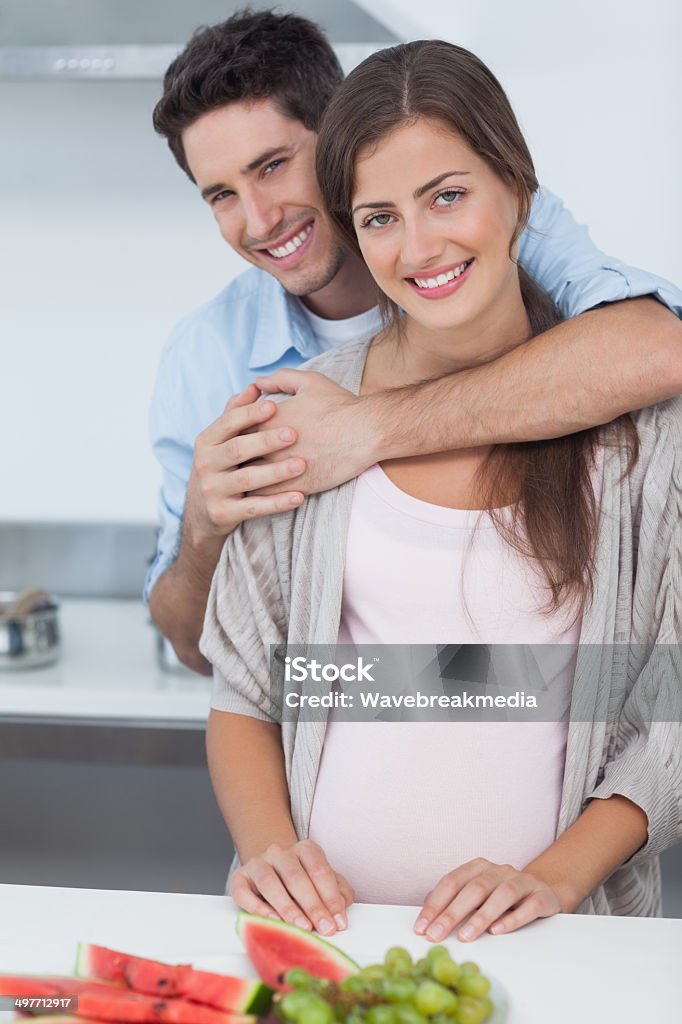 Uomo abbracciare sua moglie incinta - Foto stock royalty-free di 20-24 anni