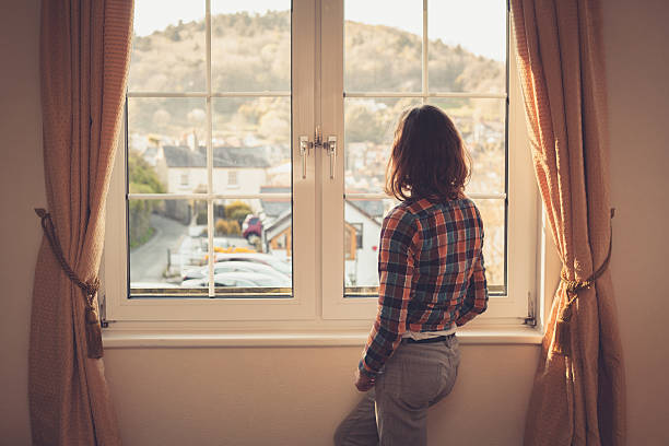istock Young woman looking out the window 497715995