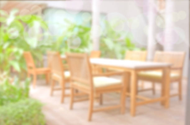 istock Blurred backyard garden background with dining wood table set. 497716408