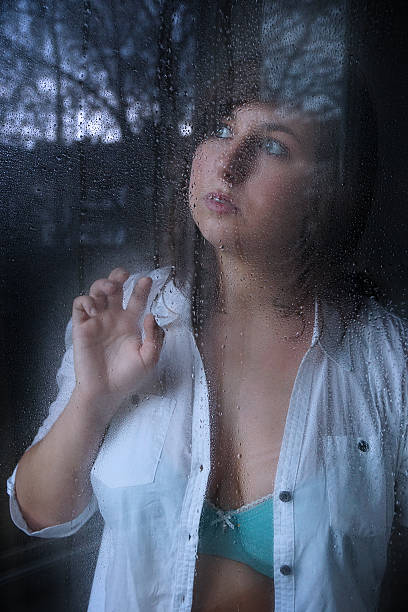 istock woman looking through window with raindrops 497741040