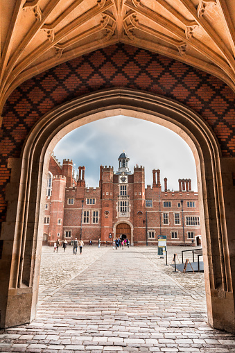 London, UK - 26 October, 2015: exterior image of Hampton Court Palace on a crisp autumn day. Hampton Court Palace is a royal palace in the London Borough of Richmond upon Thames, Greater London, in the historic county of Middlesex, and within the postal town East Molesey, Surrey. It has not been inhabited by the British Royal Family since the 18th century. The palace is 11.7 miles (18.8 kilometres) south west of Charing Cross and upstream of central London on the River Thames. Redevelopment began to be carried out in 1515 for Cardinal Thomas Wolsey, a favourite of King Henry VIII. In 1529, as Wolsey fell from favour, the King seized the palace for himself and later enlarged it. Along with St. James's Palace, it is one of only two surviving palaces out of the many owned by King Henry VIII. Vertical colour image. 