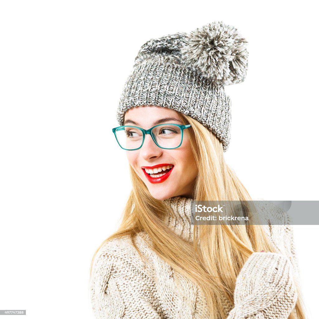 Smiling Hipster Girl in Winter Sweater and Hat on White Smiling Hipster Girl in Knitted Sweater and Beanie Hat Isolated on White. Youth Winter Fashion Concept. Eyeglasses Stock Photo