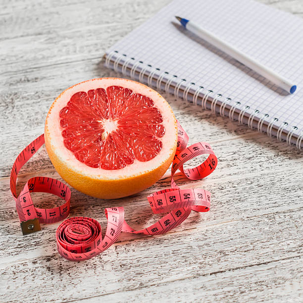 istock Notepad, grapefruit and measuring tape on a light wooden table. 497751158