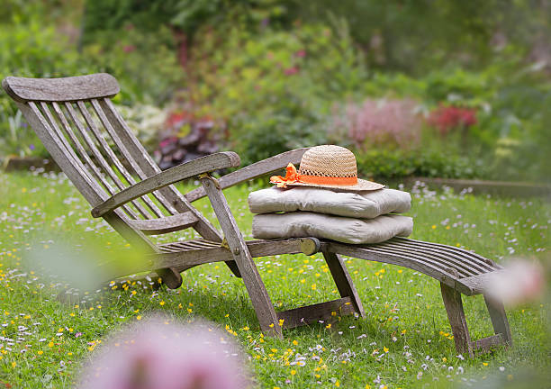 Two wooden deckchairs in a vibrant green garden.
