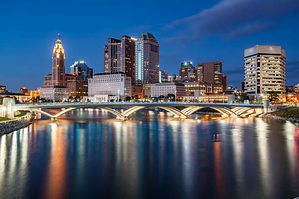 Rich Street Bridge Scioto River Downtown Columbus Ohio Skyline HDR The Scioto river reflects Downtown Columbus Ohio. The Lights of the Rich Street Bridge are seen in the foreground spanning the Scioto River.  This view is from the Scioto Mile Riverfront Park path. Streaks of the inner-city lights are reflected onto the calm river causing a mirrored effect on the waterfront in the Columbus Ohio Downtown Business District. HDR has brought out the vivid colors seen here shot in the Fall. columbus stock pictures, royalty-free photos & images