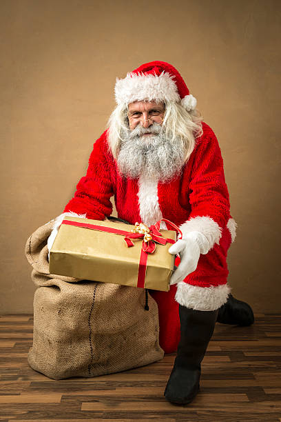 istock santa claus giving a golden present 497784302