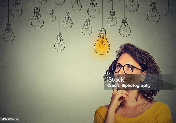 Woman In Glasses Looking Up With Light Idea Bulb Stock Photo - Download Image Now - Contemplation, Light Bulb, Individuality