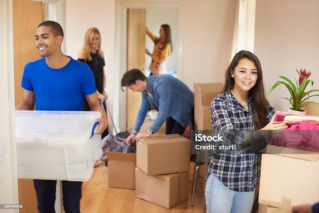 student house A group of five university students move into their shared flat , and start to unpack boxes. One male student looks to camera and smiles. Box - Container Stock Photo